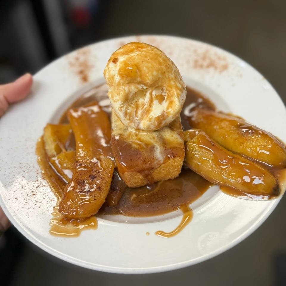 Glazed pastry dessert arranged around a scoop of ice cream on a white plate, drizzled with caramel sauce.